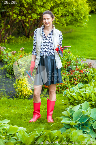 Image of smiling middle-aged woman in red rubber boots planting flowers