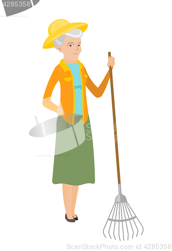 Image of Senior caucasian farmer holding gardening rake.
