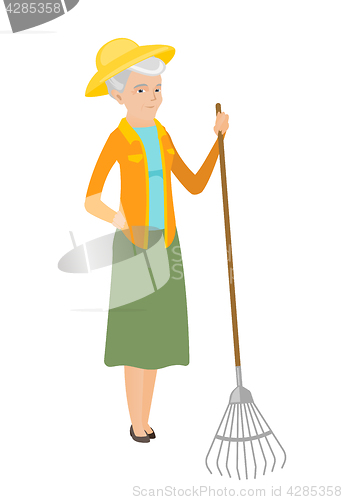 Image of Senior caucasian farmer holding gardening rake.