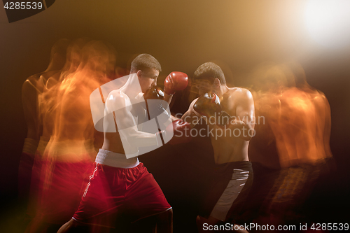 Image of The two male boxers boxing in a dark studio