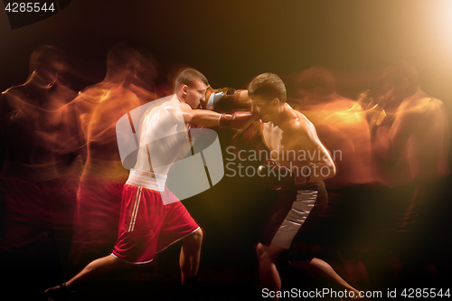 Image of The two male boxers boxing in a dark studio