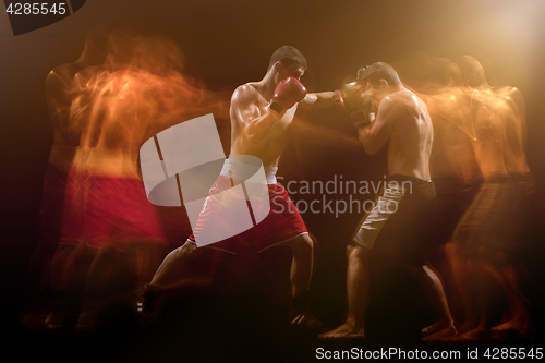 Image of The two male boxers boxing in a dark studio