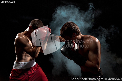 Image of Two professional boxer boxing on black smoky background,