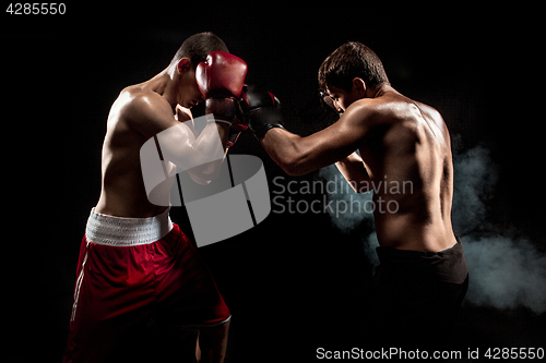 Image of Two professional boxer boxing on black smoky background,