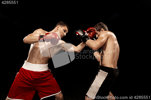 Image of Two professional boxer boxing on black background,