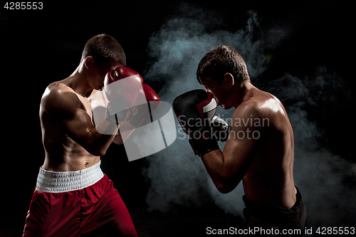 Image of Two professional boxer boxing on black smoky background,