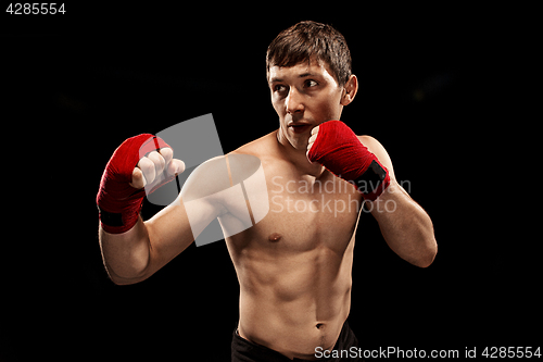 Image of Male boxer boxing in punching bag with dramatic edgy lighting in a dark studio