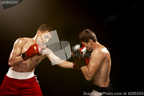 Image of Two professional boxer boxing on black background,