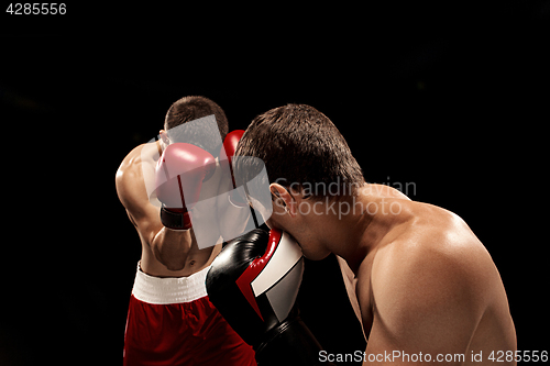 Image of Two professional boxer boxing on black background,