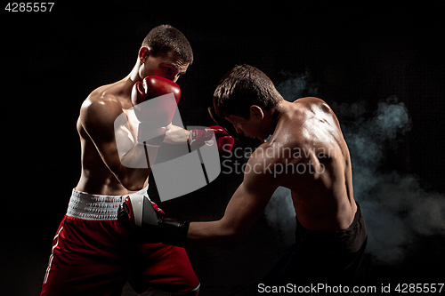 Image of Two professional boxer boxing on black smoky background,