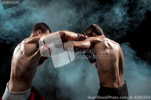 Image of Two professional boxer boxing on black smoky background,