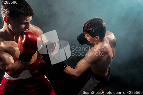 Image of Two professional boxer boxing on black smoky background,