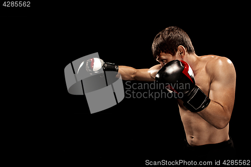 Image of Male boxer boxing in punching bag with dramatic edgy lighting in a dark studio