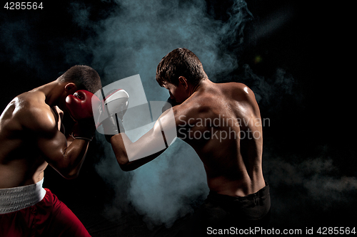 Image of Two professional boxer boxing on black smoky background,