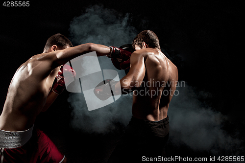 Image of Two professional boxer boxing on black smoky background,