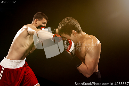 Image of Two professional boxer boxing on black background,