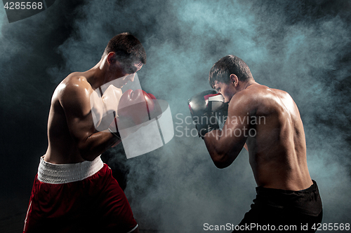 Image of Two professional boxer boxing on black smoky background,