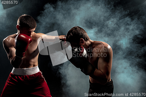 Image of Two professional boxer boxing on black smoky background,