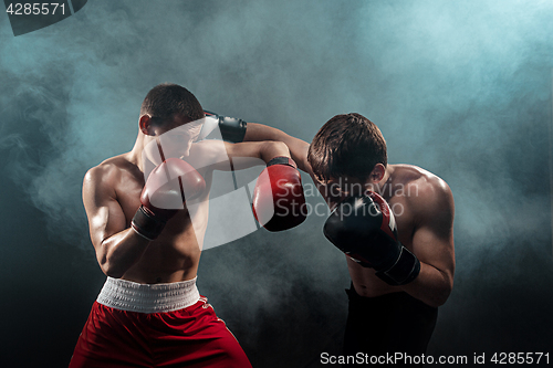 Image of Two professional boxer boxing on black smoky background,