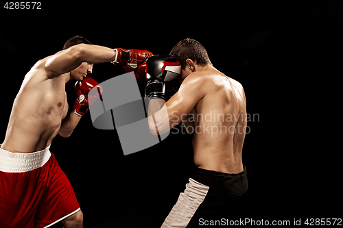 Image of Two professional boxer boxing on black background,