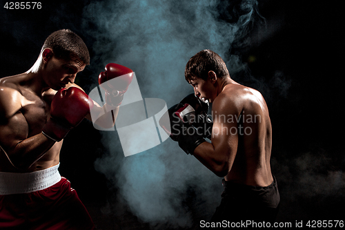 Image of Two professional boxer boxing on black smoky background,