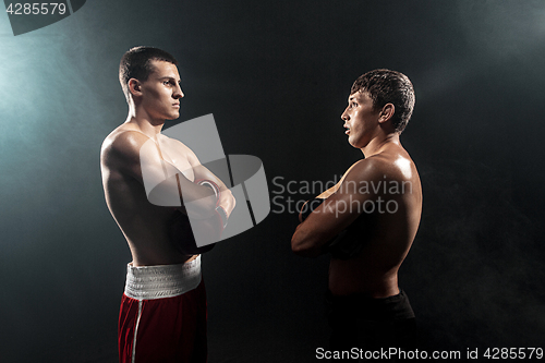 Image of Two professional boxer standing on black smoky background,