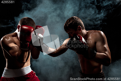 Image of Two professional boxer boxing on black smoky background,