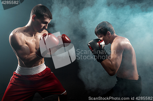 Image of Two professional boxer boxing on black smoky background,