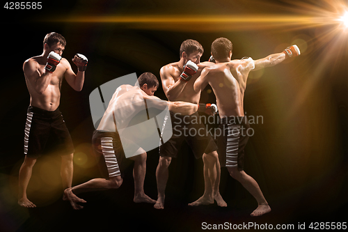 Image of Male boxer boxing in punching bag with dramatic edgy lighting in a dark studio