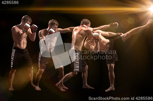 Image of Male boxer boxing in punching bag with dramatic edgy lighting in a dark studio