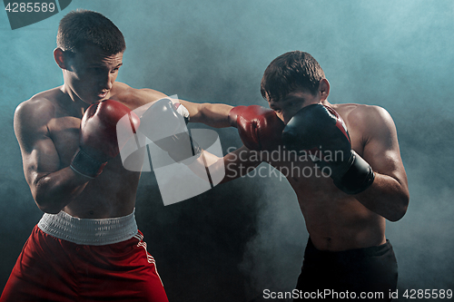 Image of Two professional boxer boxing on black smoky background,