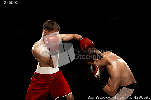 Image of Two professional boxer boxing on black smoky background,