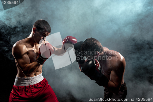 Image of Two professional boxer boxing on black smoky background,