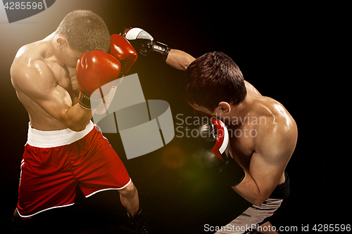Image of Two professional boxer boxing on black background,