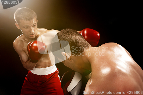 Image of Two professional boxer boxing on black background,