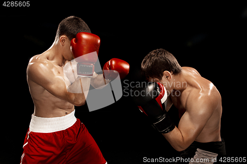 Image of Two professional boxer boxing on black background,