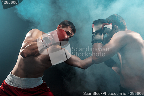 Image of Two professional boxer boxing on black smoky background,