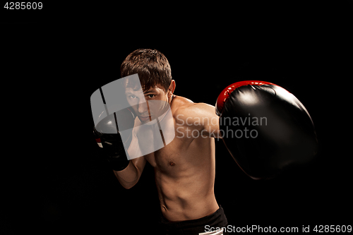 Image of Male boxer boxing in punching bag with dramatic edgy lighting in a dark studio