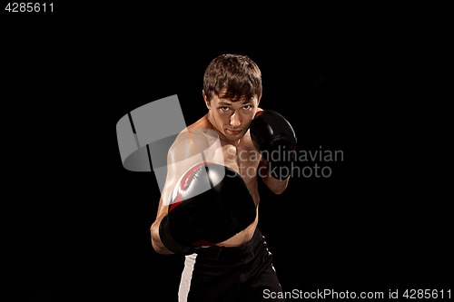 Image of Male boxer boxing in punching bag with dramatic edgy lighting in a dark studio