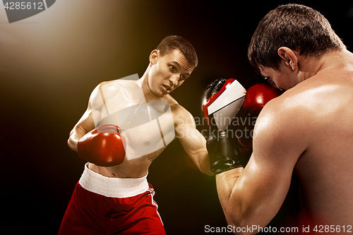 Image of Two professional boxer boxing on black background,