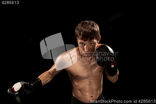 Image of Male boxer boxing in punching bag with dramatic edgy lighting in a dark studio