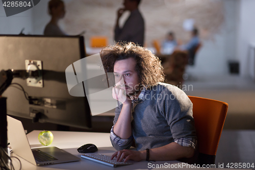 Image of man working on computer in dark office