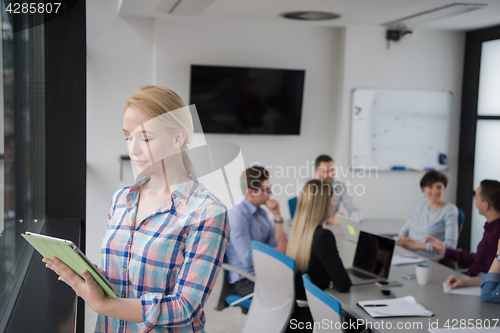 Image of Pretty Businesswoman Using Tablet In Office Building by window