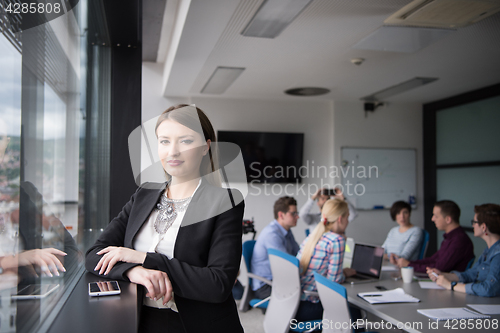 Image of Elegant Woman Using Mobile Phone by window in office building