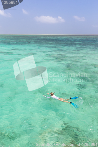 Image of Woman snorkeling in clear shallow sea of tropical lagoon with turquoise blue water.