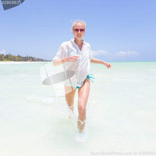 Image of Young active woman having fun running and splashing in shellow sea water.