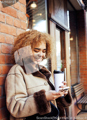 Image of young pretty african american women drinking coffee outside in c