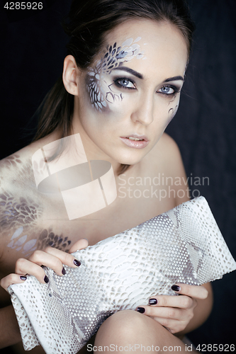 Image of fashion portrait of pretty young woman with creative make up like a snake, fashion victim with python skin clutch luxury