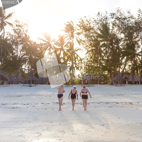 Image of Group of Senior Friends Enjoying Beautiful Sunset Walk on the Beach.