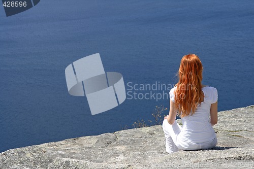 Image of Red-haired girl looking over blue water